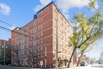 Ottawa apartment for rent - A red brick building with a green tree in front.