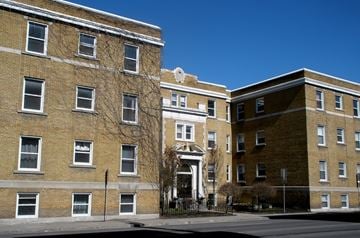 Ottawa apartment for rent - A large brick building with a black fence in front.