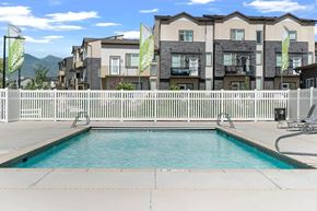 West Jordan apartment for rent - A pool in front of apartment buildings with flags on the fence.