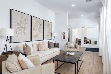 West Jordan apartment for rent - A living room with a beige couch, a coffee table, and a large abstract painting on the wall.