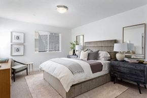 West Jordan apartment for rent - A bedroom with a large bed, a nightstand, and a chair.