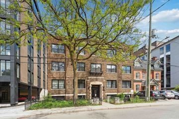 Ottawa apartment for rent - A tree in front of a building with a brick facade.