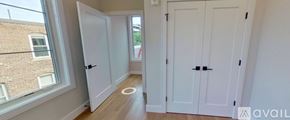 Boston apartment for rent - A hallway with white doors and a window overlooking a building.