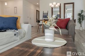 Bastrop house for rent - A living room with a white sofa, a grey armchair, a wooden coffee table, and a white vase with flowers on a round rug.