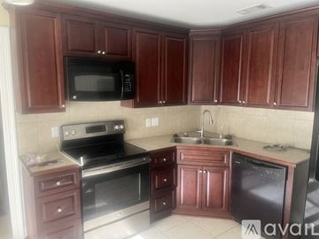 Baton Rouge house for rent - A kitchen with brown cabinets and a black microwave.