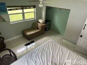 Tampa house for rent - A bedroom with a bed, chair, and window.