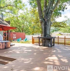 Tampa house for rent - A wooden deck with a table and chairs and a tree in the middle.