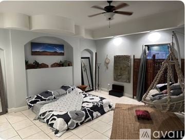 Tampa house for rent - A living room with a hanging swing chair and a large bed with a black and white pattern.