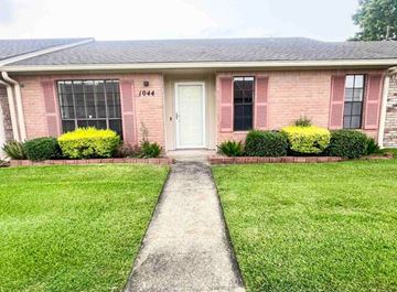 Beaumont house for rent - A house with a white door and windows with bushes in front.