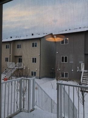 Fort Mcmurray house for rent - A view of a snowy courtyard with a building in the background.