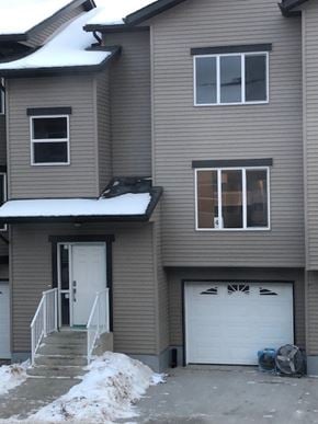 Fort Mcmurray house for rent - A two-story house with a white garage door and a black car parked in front.