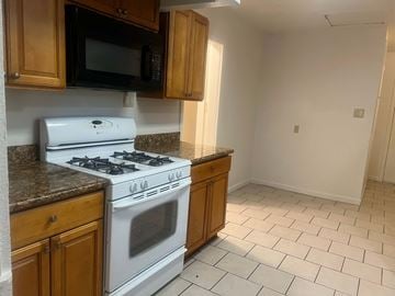 Stockton house for rent - A kitchen with a white stove and wooden cabinets.