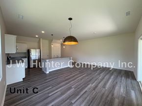 Wilson apartment for rent - A spacious room with wooden flooring and a hanging light fixture, labeled as Unit C.