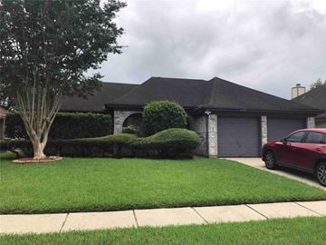 Friendswood house for rent - A red car is parked in front of a house.