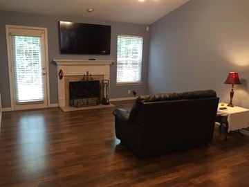Nashville house for rent - A black couch sits in a living room with a fireplace and a television.