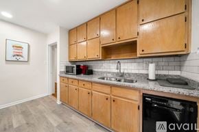 Hapeville house for rent - A kitchen with wooden cabinets and a black dishwasher.