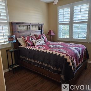 Peoria house for rent - A bedroom with a bed covered in a quilt and a lamp on a side table.
