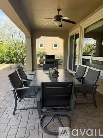 Peoria house for rent - A living room with a grey couch and a dining table with chairs.