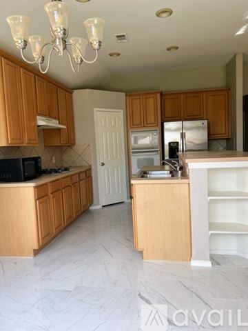 The Colony house for rent - A kitchen with wooden cabinets and a chandelier.