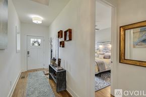 Nashville house for rent - A hallway with a rug, a wooden table with a vase and candles, and a mirror on the wall.
