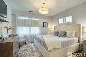 Nashville house for rent - A bedroom with a large bed, a dresser, and a window with curtains.