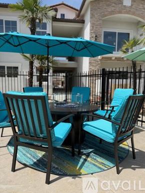 Hanford Ca apartment for rent - A patio table with four chairs and a blue umbrella.