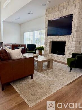 Hanford Ca apartment for rent - A living room with a stone fireplace and a flat screen TV mounted above it.