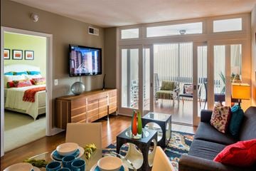 Washington apartment for rent - A living room with a couch, a television, and a glass table with various objects on it.
