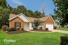 Winder house for rent - A house with a brown brick exterior and a white garage door is surrounded by a well-manicured lawn.