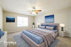 Winder house for rent - A bedroom with a large bed, a ceiling fan, and two pictures on the wall.