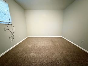 Louisville apartment for rent - A room with brown carpet and a window with blinds.