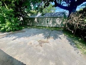 Louisville apartment for rent - A concrete driveway leads to a house with a grey siding and a white door.