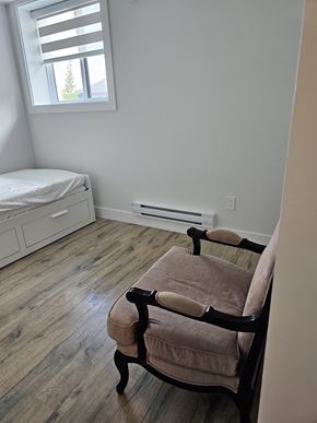 Chilliwack house for rent - A chair with a brown cushion is in the corner of a room with a window.