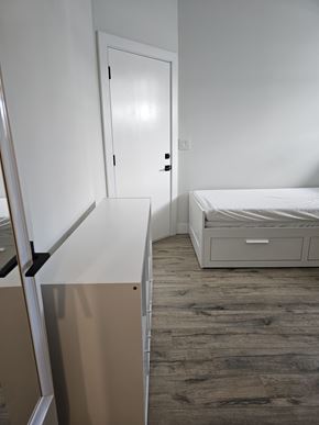 Chilliwack house for rent - A white bedroom with a bed, dresser, and mirror.