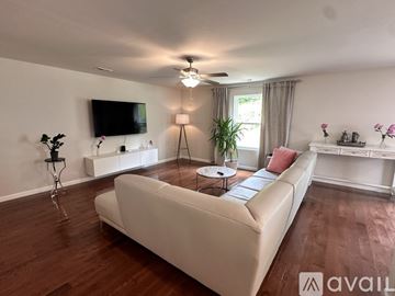 Winston-Salem house for rent - A living room with a white couch and a television mounted on the wall.