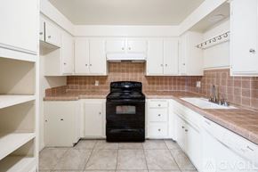 San Bernardino apartment for rent - A kitchen with white cabinets and a black oven.