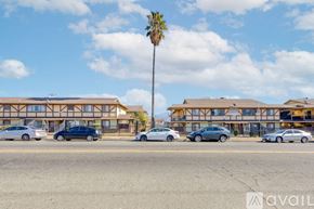 San Bernardino apartment for rent - A parking lot with cars and a building with a palm tree in front.