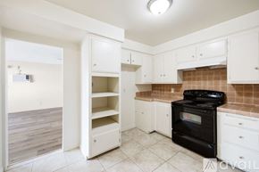 San Bernardino apartment for rent - A kitchen with white cabinets and a black stove top oven.
