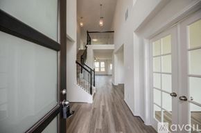 Fulshear house for rent - A hallway with a staircase and a glass door.