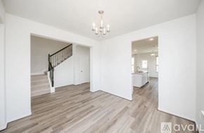 Fulshear house for rent - A spacious room with wooden flooring and a chandelier.