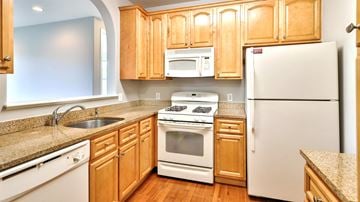 Whitehall apartment for rent - A kitchen with wooden cabinets and white appliances.