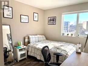 Waterloo townhouse for rent - A bedroom with a bed, desk, chair, and a window overlooking a city.