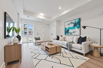 Kitchener apartment for rent - A modern living room with a white sofa, wooden side table, and a large abstract painting on the wall.
