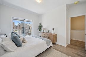 Kitchener apartment for rent - A bedroom with a large bed and a window overlooking a cityscape.