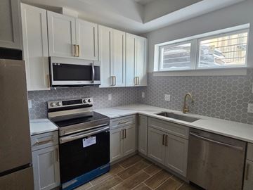Washington apartment for rent - A kitchen with a black stove top oven and white cabinets.