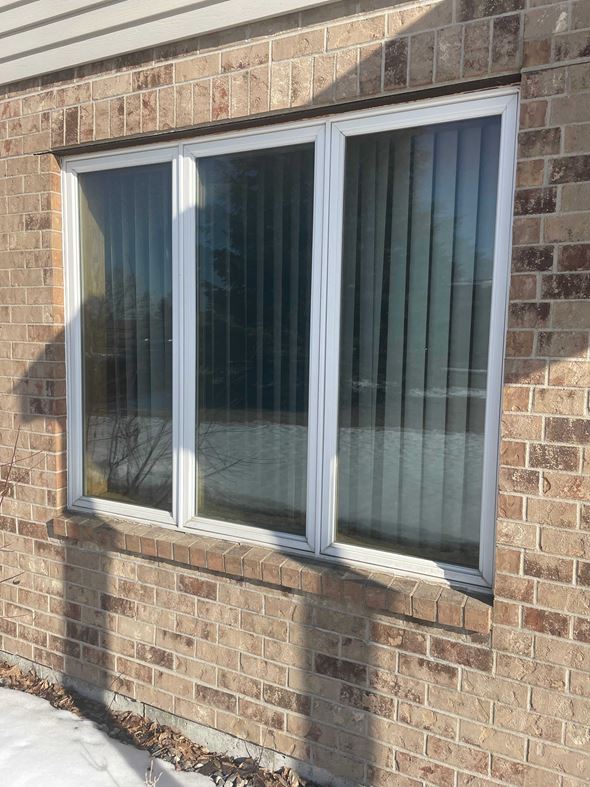 Moorhead house for rent - A window with white frames and a glass pane is on a brick wall.