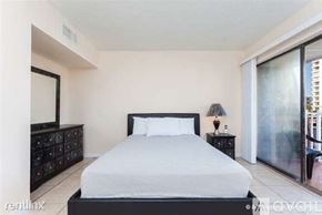 Daytona Beach apartment for rent - A bedroom with a large bed, a nightstand with a lamp, and a dresser with a mirror.