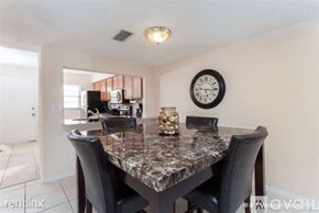 Daytona Beach apartment for rent - A dining room with a marble table and a clock on the wall.