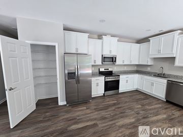 Williamsburg house for rent - A kitchen with white cabinets and a wooden floor.