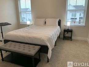 Oxford house for rent - A bedroom with a large bed and a bench in front of it.